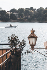 lamp in front of the seascape in rovinj and the view on the small island with trees and a boat passing in the background