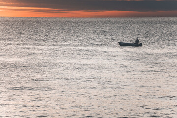 sunset over the sea in istria, croatia, with moody red clouds and a small boat in the calm water