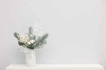 Beautiful composition with fir tree branches in vase on shelf near white wall indoors, space for...
