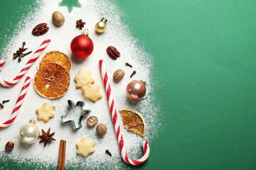 Christmas tree made with flour, cookies, candy canes and ingredients on green background, flat lay. Space for text