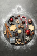 Bauble shape made with flour, Christmas decor, cookies and spices on grey table, flat lay