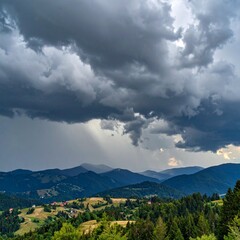 Naklejka premium Dark thunderstorm clouds forming over mountains showing dramatic natural power