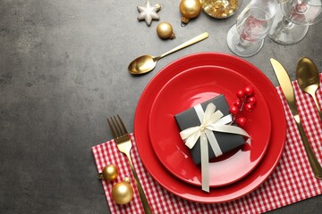 Festive table setting with Christmas gift on grey background, flat lay. Space for text