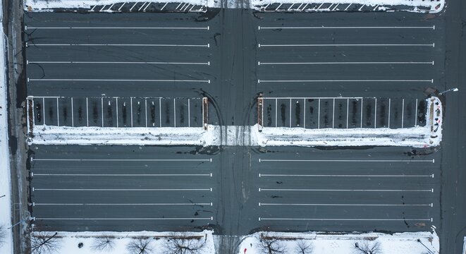 Aerial view of an empty parking lot in winter with snow on the edges.