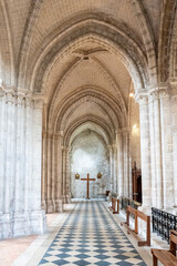 Hall inside gothic Cathedral made in stone leading to a cross at the end of the corridor.