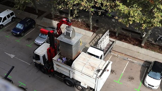 Waste management truck collecting garbage from urban bin. Urban sanitation truck with hydraulic crane. Spain, Barcelona 13.10.2025