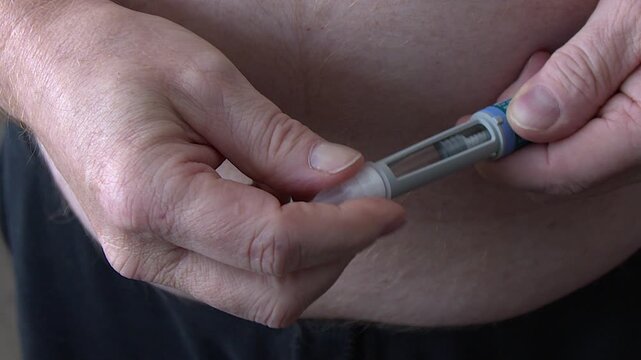 Needle cap is screwed onto injectable medication pen, close-up view