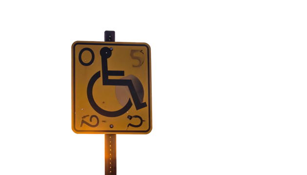 Yellow accessible sign illuminated in dark, depicting a person in wheelchair for disability access