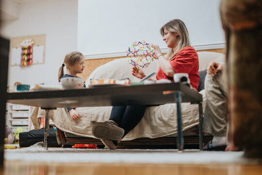 A woman and a child engage in an interactive learning activity involving creative tools, creating a warm and educational environment.
