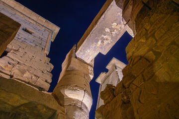 Extreme low angle view capturing the massive ancient stone lintel and illuminated columns of the...