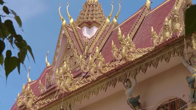 Golden chofas (serpent like roof decoration) on the tiled roof of Wat Kampong Phluk Buddhist temple are decorated with light garlands for celebration. Siem Reap, Cambodia. Shot in motion 