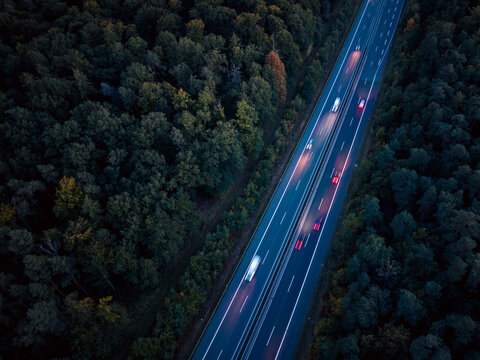 An aerial view of the highway traffic at night between the autumn forest