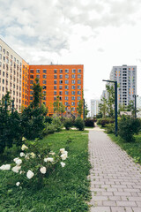Modern residential courtyard with green lawns, flowers, paved walkways surrounded by colorful...
