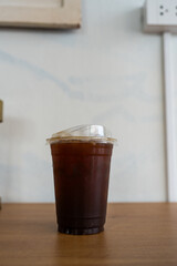 Iced black coffee americano in take away cup on wood table