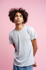 Young man posing with curly hair on pink background