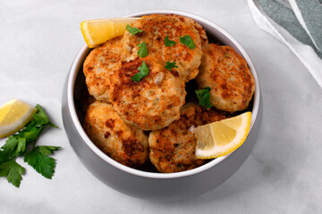 Haddock fish cakes made of mince and fried served with lemon in a gray bowl on white