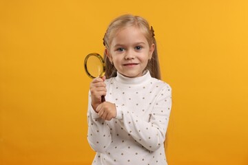 Little girl with magnifying glass on yellow background