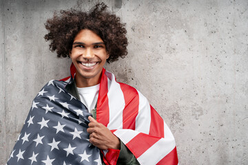 Smiling young man proudly wrapped in American flag