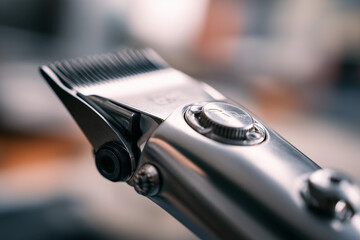 Close-up view of hair clippers during a modern haircut in a bustling barbershop setting focused on men's grooming and styling techniques