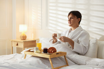 Man having delicious breakfast in bed, space for text. Hotel room service