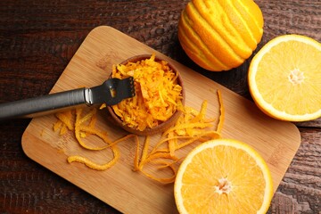 Orange zest, fresh fruits and zester tool on wooden table, flat lay