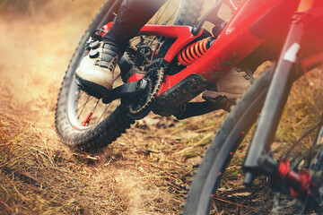 Close-up of red mountain bike on dirt trail during downhill ride. Focus on suspension, pedals and mud details. Gravity sport and endurance action.