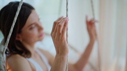 Dreamy girl swinging slowly in soft morning home closeup. Woman in hanging chair