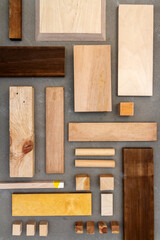 Flat lay of various wood and plywood pieces on concrete texture. Carpentry background.