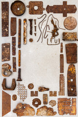 A group of various old rusty bits and pieces arranged on a concrete surface. Old rusty nuts, bolts, nails and other parts flay lay on gray background.