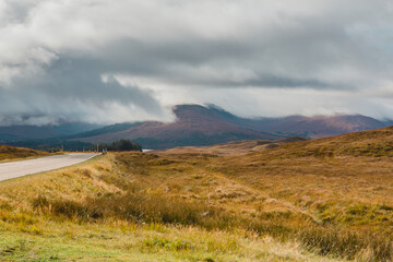 Glencoe, United Kingdom - October 11 2025: Stunning beauty of Glencoe National Park in the Scottish Highlands on a sunny autumn afternoon with mystical-looking mountains shrouded by dramatic clouds