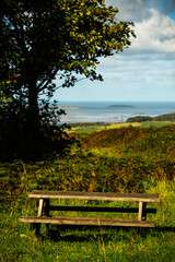 Fototapeta premium Wooden bench overlooking Welsh coast and distant island