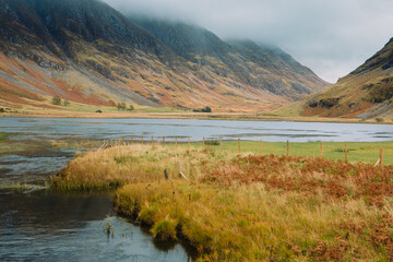 Loch Achtriochtan is a small lake in Glencoe, Scotland, famous for the iconic River Coe and the white Achnambeithach Cottage, which sits at its south end in the Scottish Highlands next to a waterfall