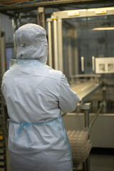 Worker on the conveyor. A worker in a white coat. Food production.