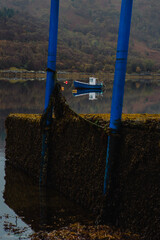 A boat is seen with it's refection in the tranquil waters of Loch Sunart, Scottish Highlands, on a peaceful day

