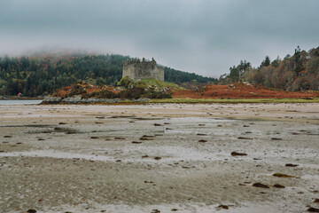 A dramatic and atmospheric photograph of the ruined medieval Castle Tioram (pronounced "Cheerum"), the former stronghold of the Clanranald branch of the MacDonalds - in Loch Moidart