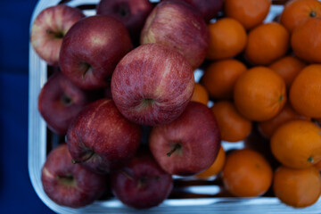 Fresh red apples and vibrant oranges displayed together in a fruit market basket