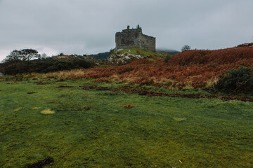 A dramatic and atmospheric photograph of the ruined medieval Castle Tioram (pronounced "Cheerum"), the former stronghold of the Clanranald branch of the MacDonalds - in Loch Moidart