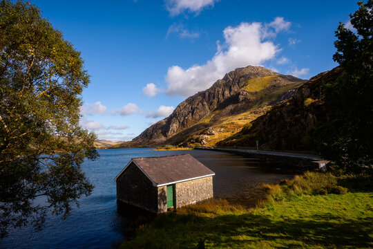Llyn Ogwen boathouse with Tryfan mountain in golden sunlight, Snowdonia, Wales - Powered by Adobe