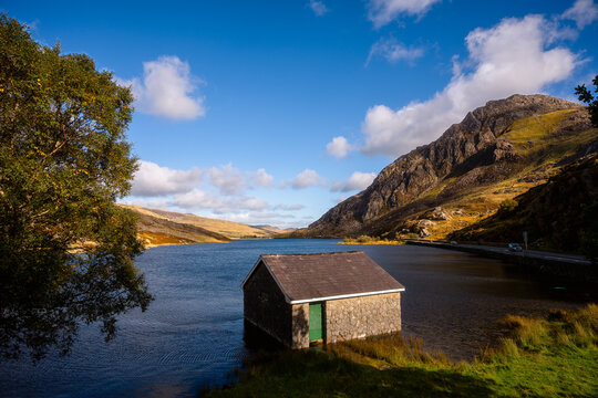 Stone boathouse on Llyn Ogwen with Tryfan mountain in sunlight, Snowdonia, Wales