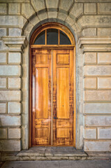 French Hardwood Teak Doors with a Transom on a Grey Stone Building Wall.