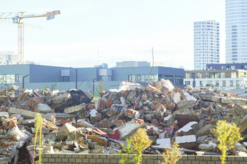 Demolished structure rubble mound against contemporary urban residential architecture and tower crane equipment. Urban redevelopment momentum, construction site reality, and city expansion narrative. 