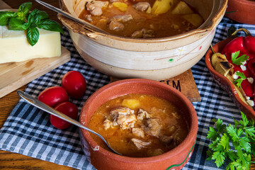A warm bowl of cooked potato soup placed on a table, showcasing its creamy texture, soft vegetables, and homemade appearance. The natural lighting highlights the comforting and rustic feel of the dish