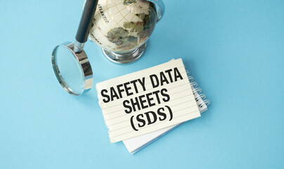 A globe sits on a table with a piece of paper that says Safety Data Sheets (SDS)