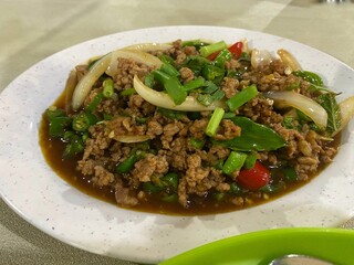 White plate filled with a delicious Thai Holy Basil Stir-fry with ground meat or known as Pad Kra Pao. Food photography concept.