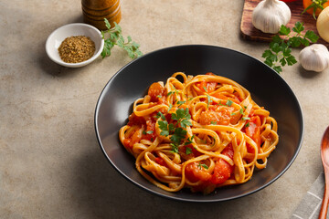 Fettuccine pasta with fresh tomatoes sauce in white plate.topped with parmesan cheese and parsley.