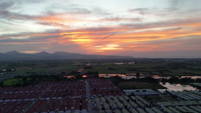 Aerial drone footage ascending over Naic, Cavite, Philippines during a breathtaking sunset, revealing rice fields, rural houses, and glowing orange skies in a peaceful provincial countryside landscape