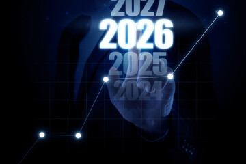 Businessman choosing 2026 year among others from 2024 to 2027 on virtual screen with graph against dark blue background, closeup. New year goals and plans