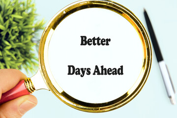 A hand holds a magnifying glass focusing on the phrase Better Days Ahead. Green foliage and a pen are visible in the background, conveying a sense of encouragement and clarity