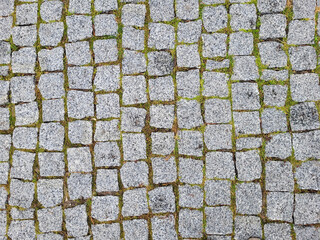 The old pavement made of gray granite tiles in the city square