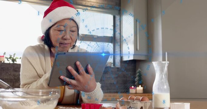 Senior woman loading baking recipe by tapping tablet, mixing batter with floating animated steps